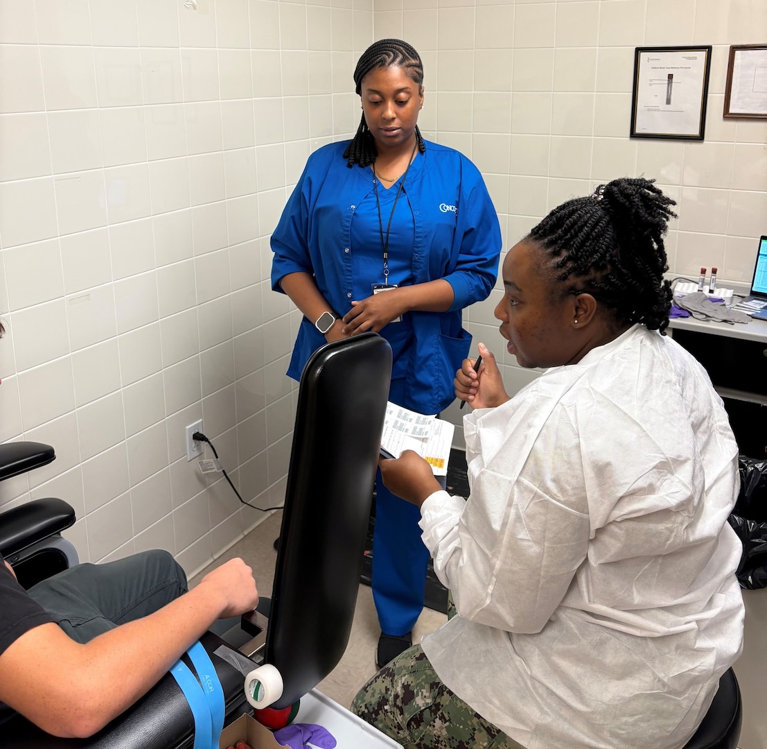 Metuschelah Francois, phlebotomy extern, (left) learns MEPS procedures from Petty Officer 2nd Class Litaly Pugh (right) during externship training. The Jacksonville MEPS team welcomed the first two phlebotomy externs to help assist with collecting vitals, drawing blood and urine samples and conducting vision and audio screenings.