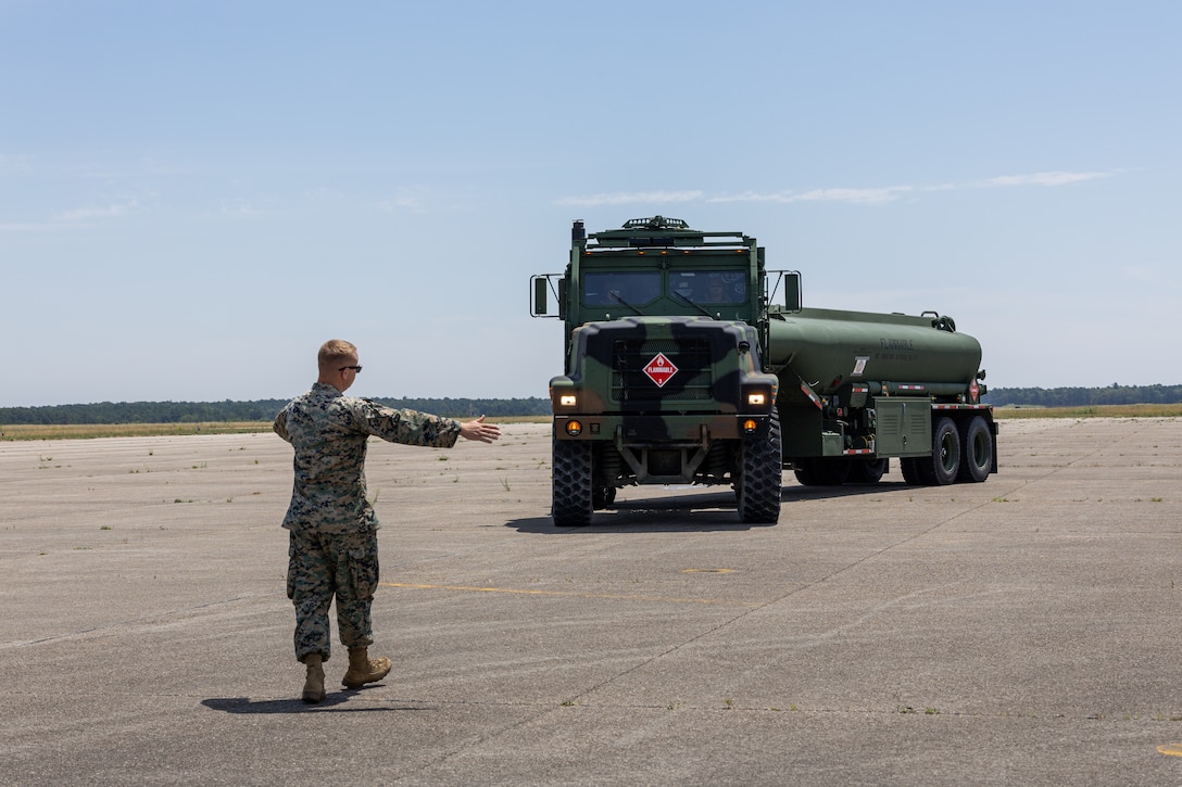 U.S. Marine Corps Lance Cpl. Landen Brown, an expedient fuel technician with Marine Wing Support Squadron 471, Marine Aircraft Group 41, 4th Marine Aircraft Wing, guides a fuel truck to an F-5N Tiger II aircraft assigned to Marine Fighter Training Squadron (VMFT) 402 during Atlantic Alliance 2025 at Joint Base Cape Cod, Massachusetts, July 3, 2025. VMFT-402’s purpose in Atlantic Alliance is to support and enhance Navy-Marine Corps amphibious operations by providing advanced fighter training and integrating air combat capabilities into joint and allied exercises along the East Coast. (U.S. Marine Corps photo by Sgt. Emely Gonzalez)