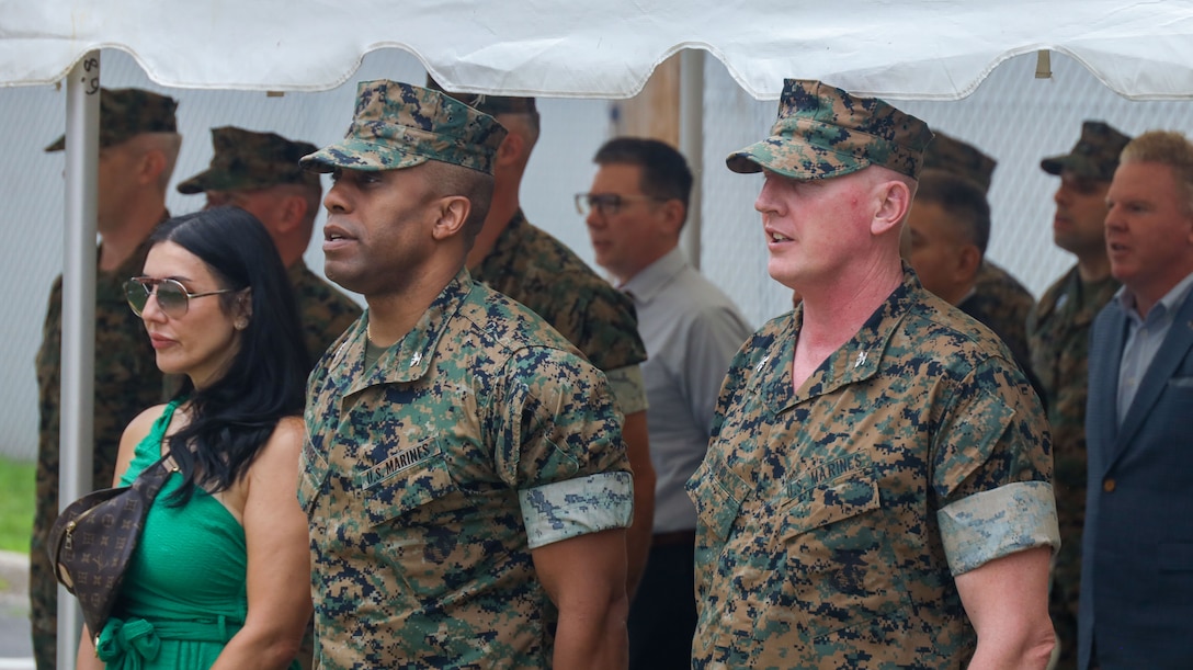 U.S. Marine Corps Col. Robert Jones, incoming commanding officer of 1st Marine Corps District (MCD), and Col. Charles Nicol, commanding officer of 1st MCD, stand at attention for the playing of Anchors Aweigh and the Marine Corps Hymn during the opening ceremony of the Robert Mullan Center, Fort Hamilton, New York, July 17, 2025. The ceremony was held to honor the opening of 1st MCD's new headquarters after relocating from Garden City, New York.