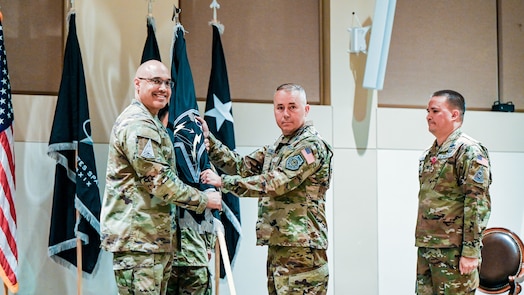  United States Space Force Lt. Gen. David N. Miller, Jr. (left), commander of Space Operations Command, passes the Mission Delta 4 flag to Col. Aaron Cochran (center) at a Change of Command ceremony at Buckley Space Force Base, Colo., July 15, 2025. Cochran took over command of the U.S. Space Force's Missile Warning and Tracking unit from U.S. Space Force Col. Bobby Schmitt (right). (U.S. Space Force photo by Dave Grim)