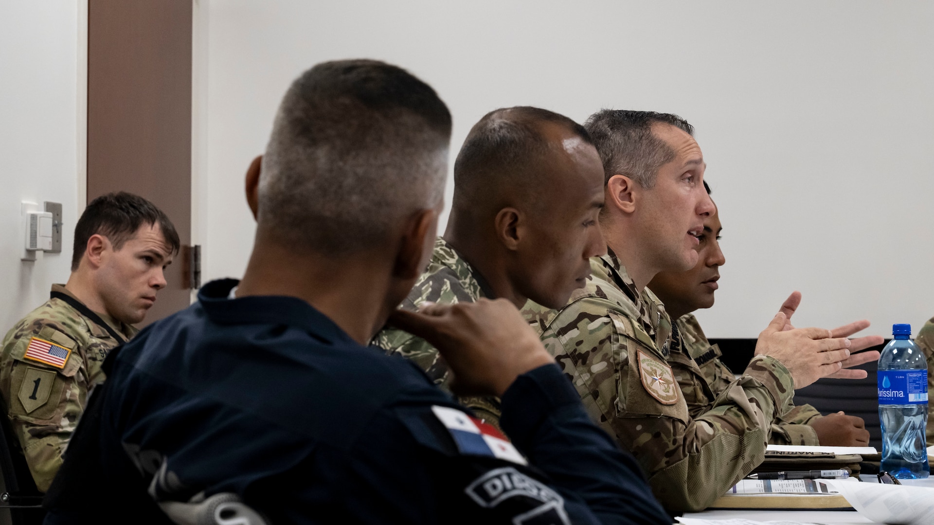 A U.S. service member talks while sitting at a table with U.S. and Panamanian service members.