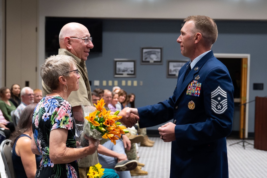 U.S. Air Force Chief Master Sgt. Derek Neill, incoming 17th Training Wing command chief, gives his first coin as command chief to his father during the change of responsibility ceremony at the Powell Event Center, Goodfellow Air Force Base, Texas, July 16, 2025. Command chiefs advise the commander and senior leadership on military readiness, mission effectiveness, morale, welfare, discipline and fitness of enlisted personnel. (U.S. Air Force photo by Airman 1st Class Brian Lummus)