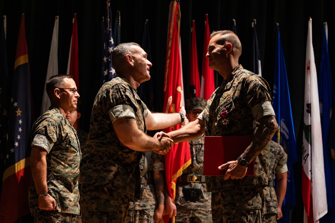 U.S. Marine Corps Brig. Gen. Ralph J. Rizzo Jr., center left, commanding general, Marine Corps Installations East-Marine Corps Base Camp Lejeune, shakes hands with Col. Garth W. Burnett, outgoing commanding officer, Marine Corps Air Station (MCAS) New River, during a change of command ceremony at MCAS New River in Jacksonville, North Carolina, July 17, 2025. The ceremony represented the transfer of responsibility, authority and accountability from the outgoing to the incoming commanding officer. (U.S. Marine Corps photo by Cpl. Loriann Dauscher)