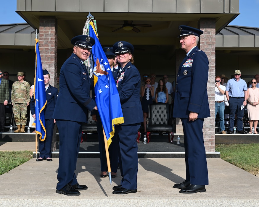 U.S. Air Force Col. Angelina Maguinness, outgoing 17th Training Wing commander, passes the guidon to Maj. Gen. Matthew Davidson, 2nd Air Force commander, relinquishing command during the change of command ceremony at Goodfellow Air Force Base, Texas, July 17, 2025. Passing the guidon represents the transfer of leadership responsibilities to the next commander. (U.S. Air Force photo by Staff Sergeant Nathan Call)