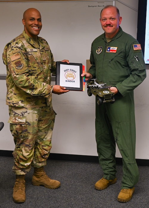 Chief Master Sgt. Jonathan Birk (left), 433rd Airlift Wing command chief, presents the items associated with the Jeep Chief tradition to Chief Master Sgt. Jeremy Everly (right), 433rd Aeromedical Evacuation Squadron senior enlisted leader, during an informal ceremony at Joint Base San Antonio-Lackland, Texas, July 12, 2025.