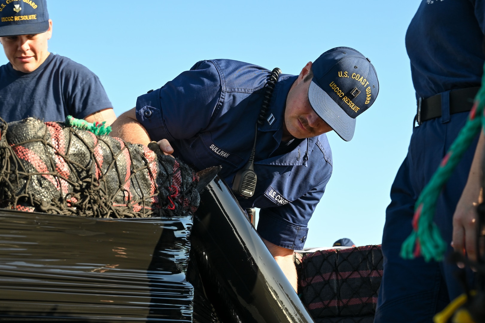 U.S. Coast Guard Lt. Logan Sullivan, an engineering officer assigned to USCGC Resolute (WMEC 620), wraps bails of illicit narcotics during a drug offload at Coast Guard Sector St. Petersburg, July 17, 2025. Resolute’s crew offloaded nearly 12,600 pounds of cocaine, worth an estimated $93.2 million following a 59-day patrol in the Eastern Pacific. (U.S. Coast Guard photo by Petty Officer 1st Class Riley Perkofski)