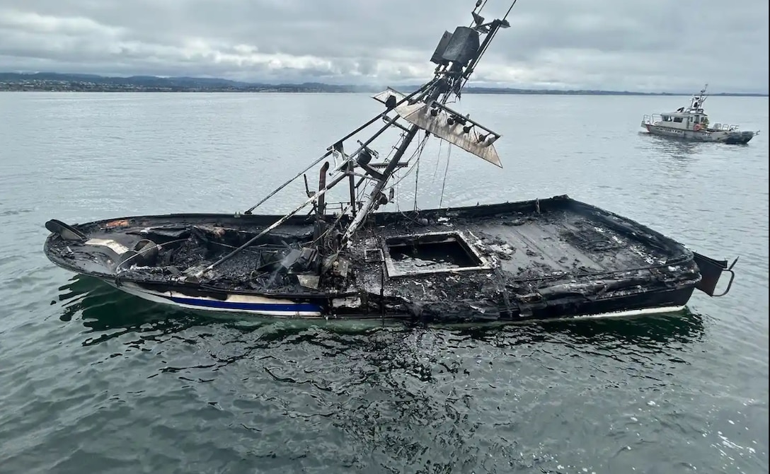 A burnt boat is seen taking on water following a boat fire.