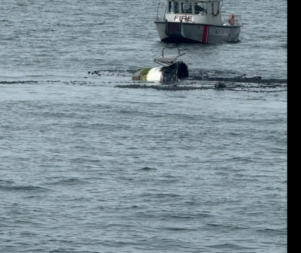 A boat's stern is seen just above the surface of the water as it sinks.
