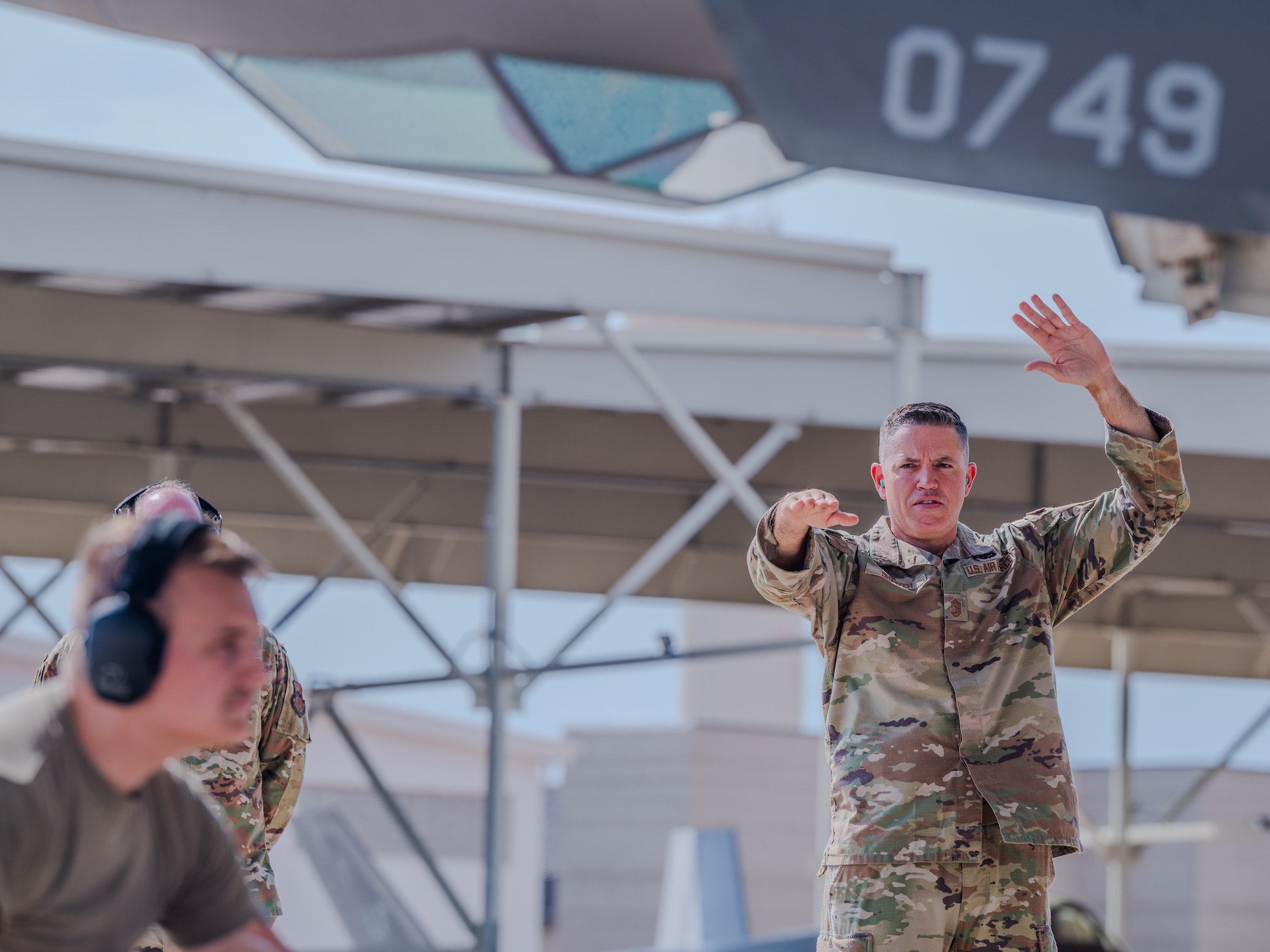 U.S. Air Force Chief Master Sgt. Jason Shaffer, 56th Fighter Wing command chief, uses hand gestures to direct a jet during launch on the flightline, July 16, 2025, at Luke Air Force Base, Arizona.