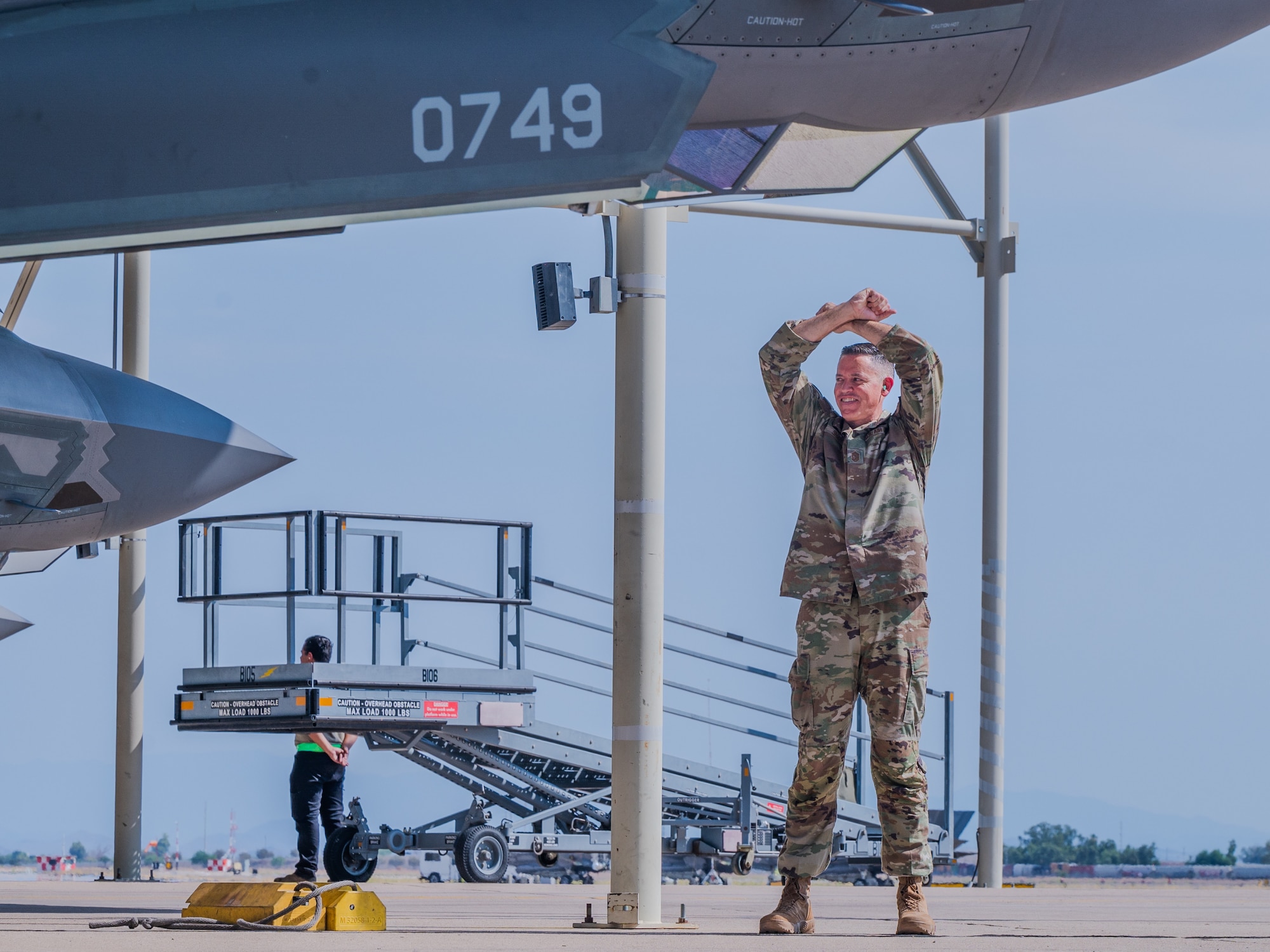 U.S. Air Force Chief Master Sgt. Jason Shaffer, 56th Fighter Wing command chief, uses hand gestures to hold a jet prior to launching from the flightline, July 16, 2025, at Luke Air Force Base, Arizona.