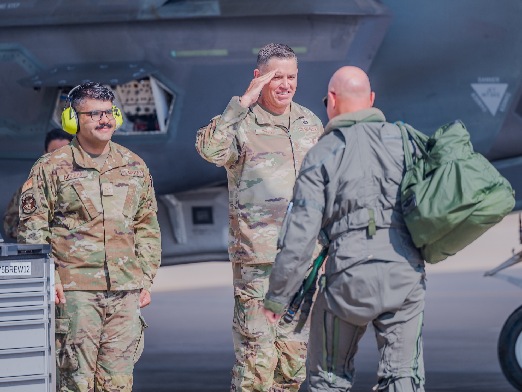 U.S. Air Force Chief Master Sgt. Jason Shaffer (center), 56th Fighter Wing command chief, and Airman First Class Ninort Audisho (left), 310th Aircraft Maintenance Unit crew chief, greet Brig. Gen. David Berkland (right), 56th Fighter Wing commander, on the flightline, July 16, 2025, at Luke Air Force Base, Arizona.
