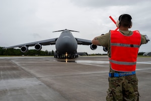 A U.S. Air Force Airman assigned to the 730th Air Mobility Squadron signals a U.S. Air Force C-5M Super Galaxy aircraft to stop during exercise Resolute Force Pacific (REFORPAC) 2025 at Misawa Air Base, Japan, July 16, 2025.