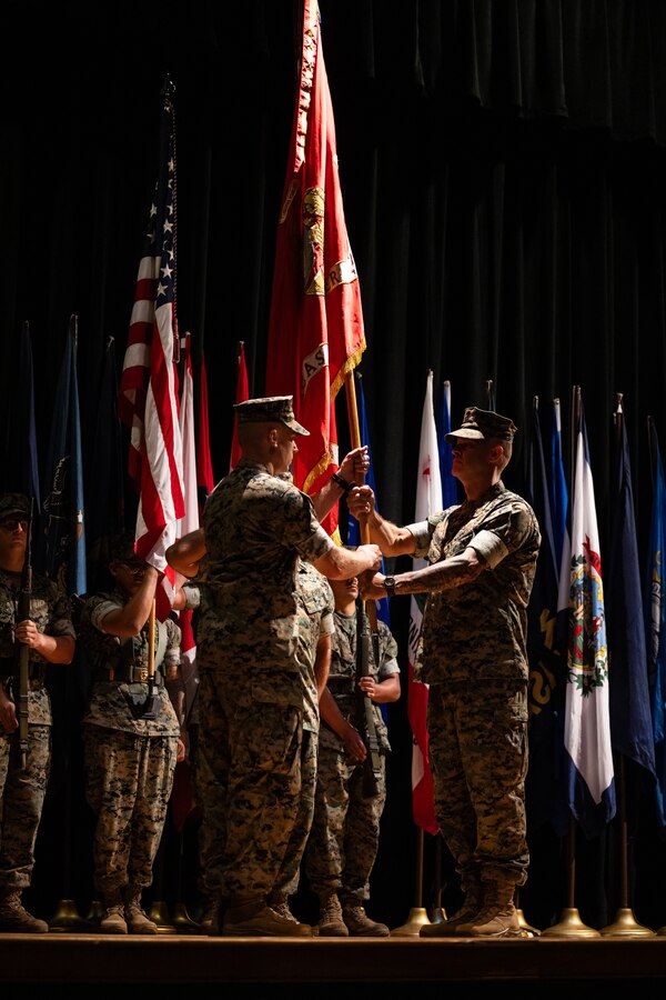 U.S. Marine Corps Col. Garth W. Burnett, right, outgoing commanding officer, hands the unit guidon to Col. Thomas Farrington II, incoming commanding officer, Marine Corps Air Station (MCAS) New River, during a change of command ceremony at MCAS New River in Jacksonville, North Carolina, July 17, 2025. The ceremony represented the transfer of responsibility, authority and accountability from the outgoing to the incoming commanding officer. (U.S. Marine Corps photo by Cpl. Loriann Dauscher)