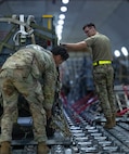 U.S. Air Force Airmen secure cargo on to a Boeing 747 Aircraft