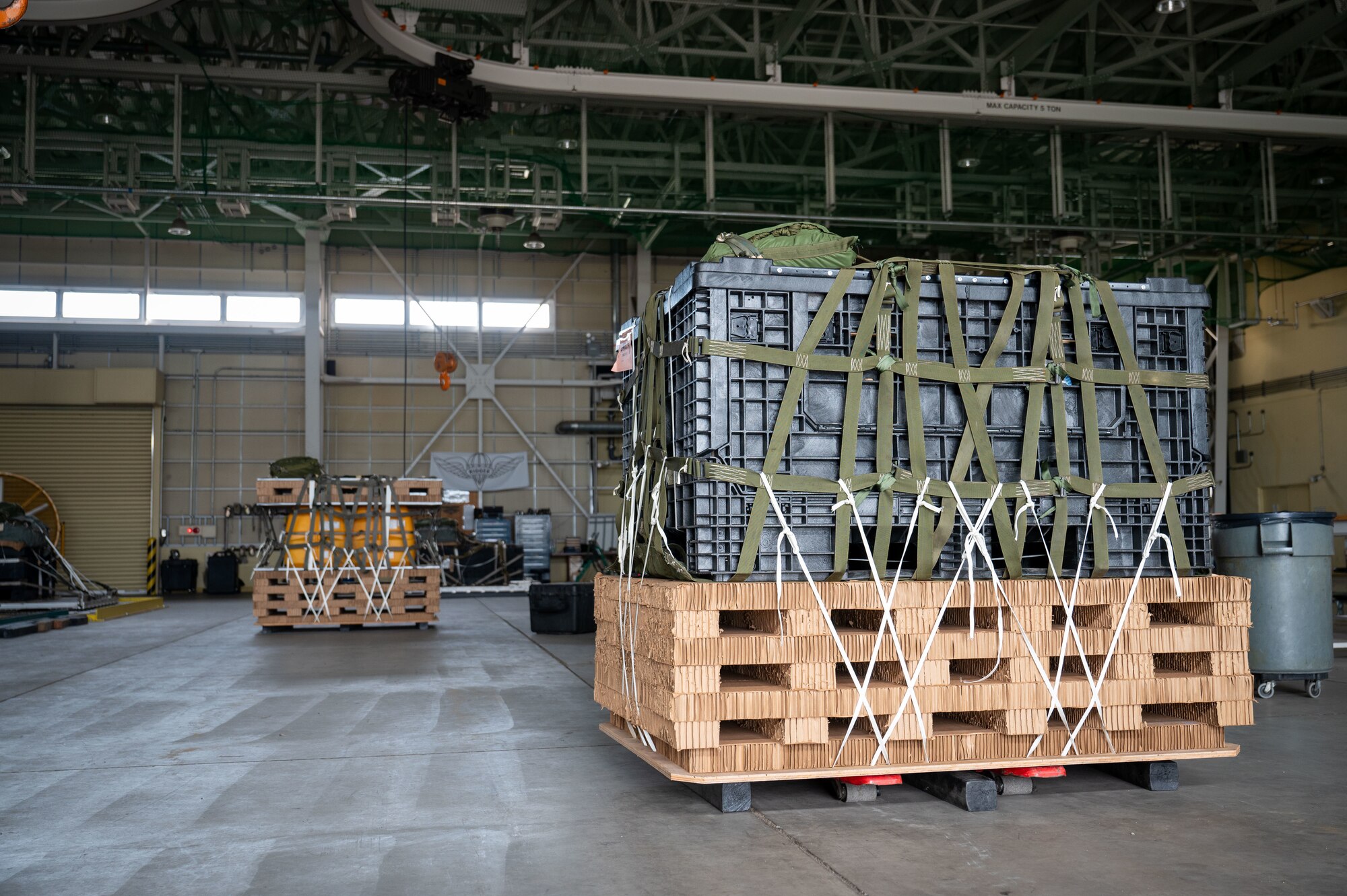 Palletized cargo bundles sit inside a hangar.
