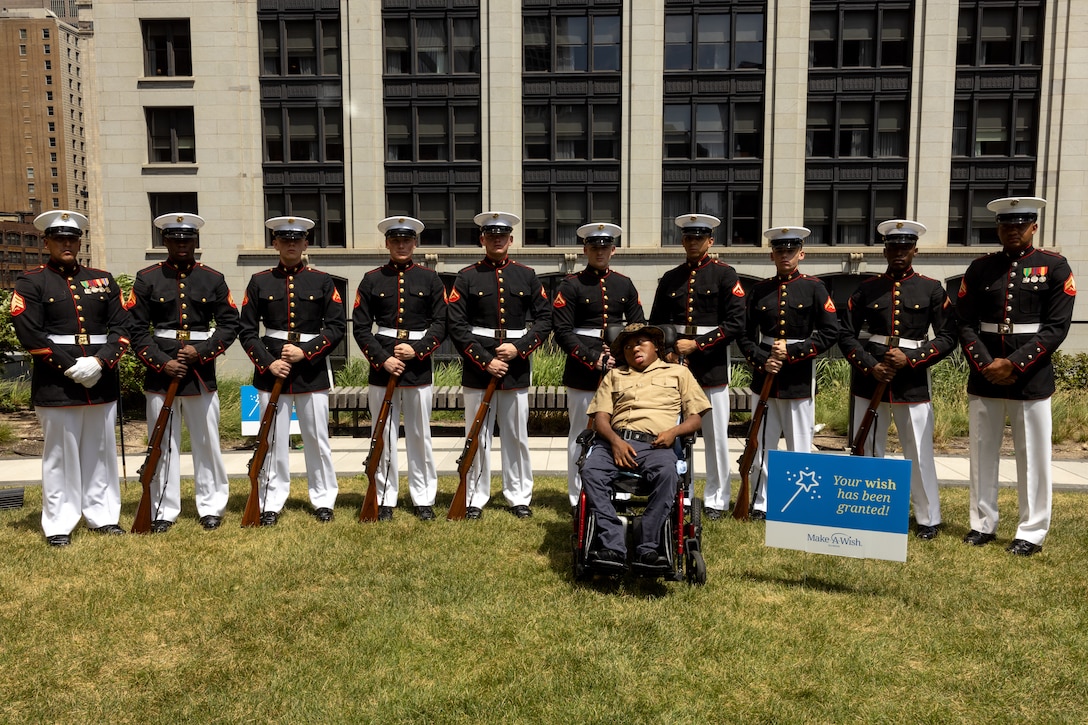 The U.S. Marine Corps Silent Drill Platoon, assigned to Special Purpose Marine Air-Ground Task Force-250, and Jamaria Peters, a Make-A-Wish recipient, pose for a photo during a ceremony for him at the Willis Tower for Marine Week Chicago, July 11, 2025. The event featured a performance from the drill team, music from the Quantico Marine Band, and the appearance of drill instructors from Marine Corps Recruit Depot San Diego.