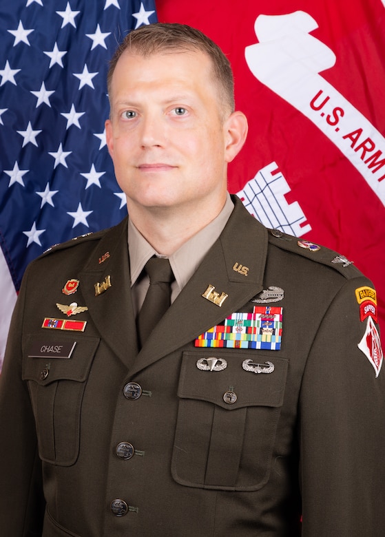 A man in a military uniform with the U.S. flag and USACE flag behind him