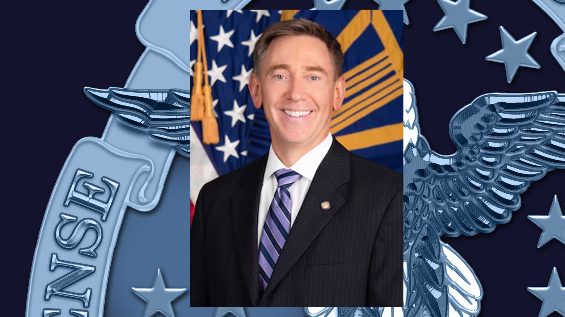Headshot of man with brown hair wearing a black suit, white shirt and blue diagonally-striped tie.