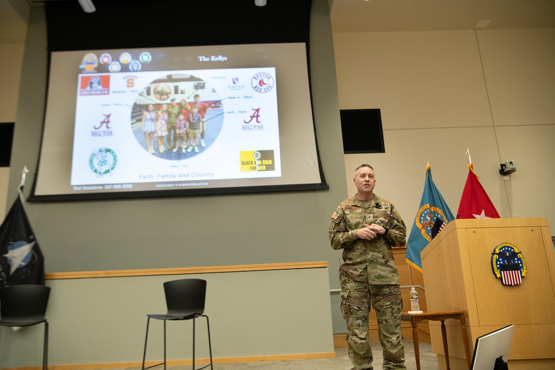 uniformed man stands on stage next to podium