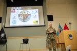 uniformed man stands on stage next to podium