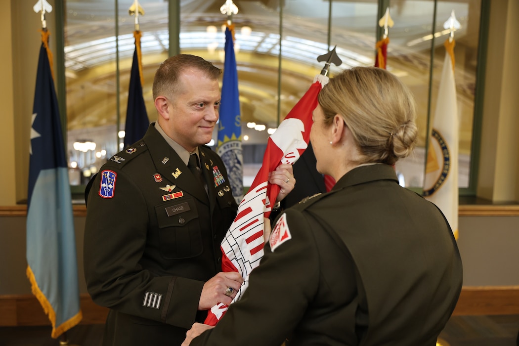 Military officer receives a military flag from another military officer