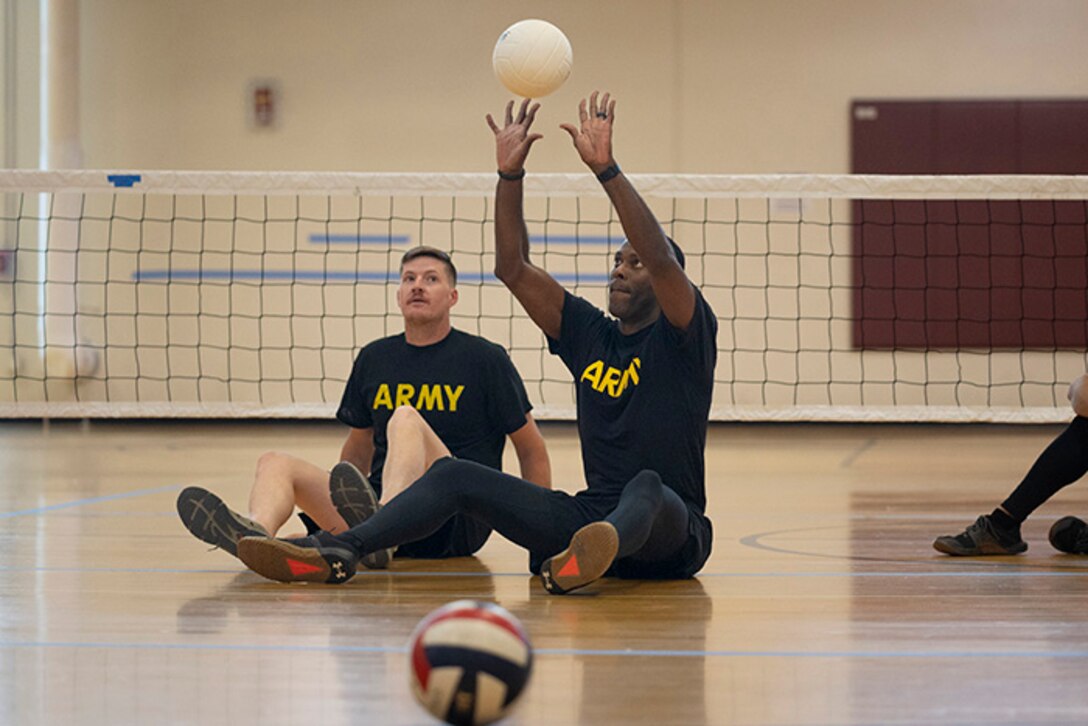 U.S. Army Staff Sgt. Derrick Thompson hits the volleyball as teammate Staff Sgt. Coty Tuck looks on during training drills at sitting volleyball practice during the 2025 Department of Defense Warrior Games at Fort Carson, Colorado, July 13, 2025.