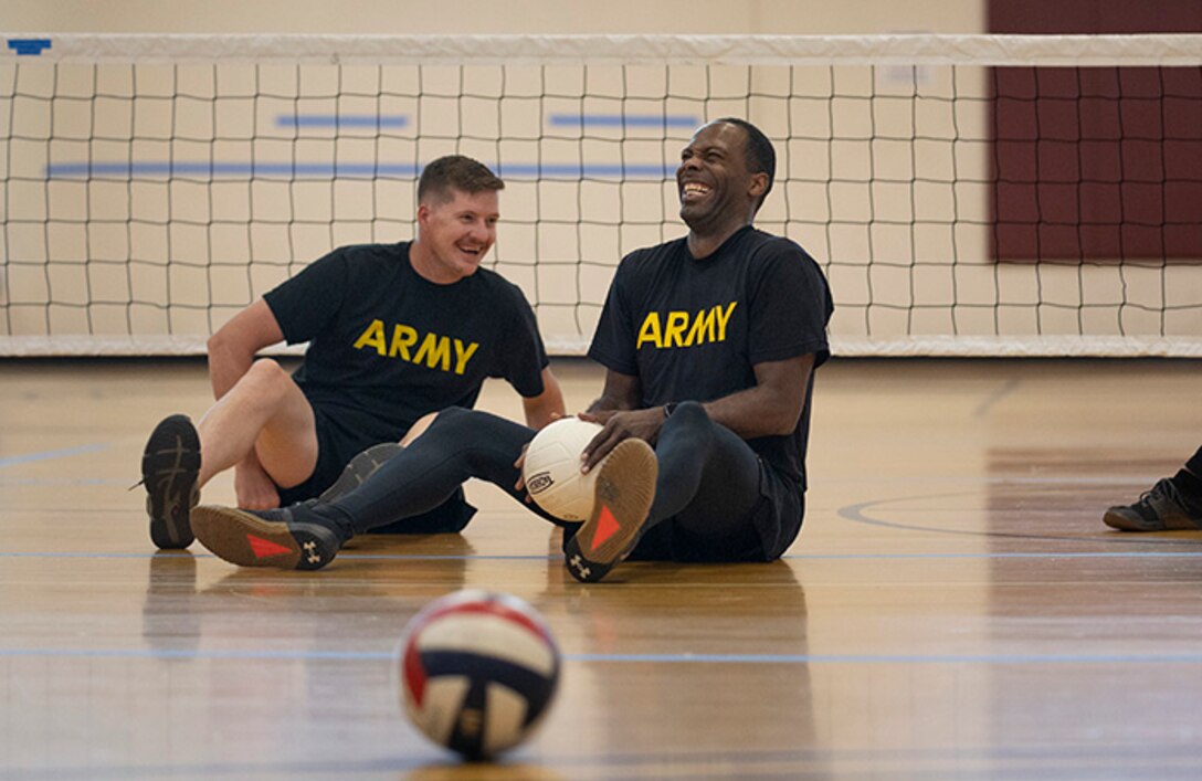 U.S. Army Staff Sgt. Coty Tuck, left, and U.S. Army Staff Sgt. Derrick Thompson, right, laugh while participating in training drills at sitting volleyball practice during the 2025 Department of Defense Warrior Games at Fort Carson, Colorado, July 13, 2025.