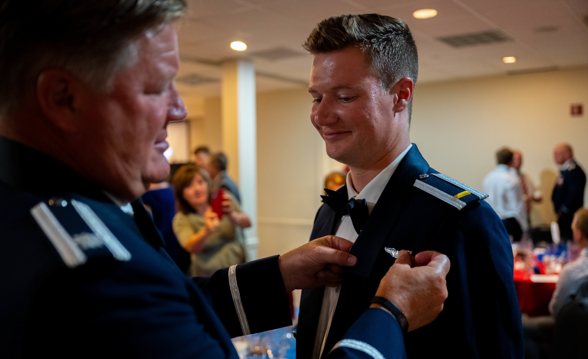 A family member pins silver wings on their graduate during the graduation ceremony of Class 25-12 at Laughlin Air Force Base, Texas, July 17, 2025.  Graduating student pilots were awarded silver wings as a symbol of successfully completing undergraduate pilot training. (U.S. Air Force photo by Airman 1st Class Darryl Keith.)