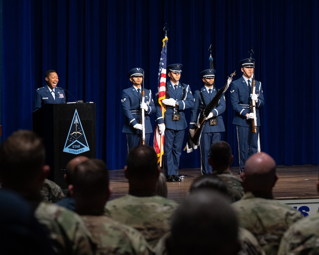 Woman singing and people in uniform standing at attention