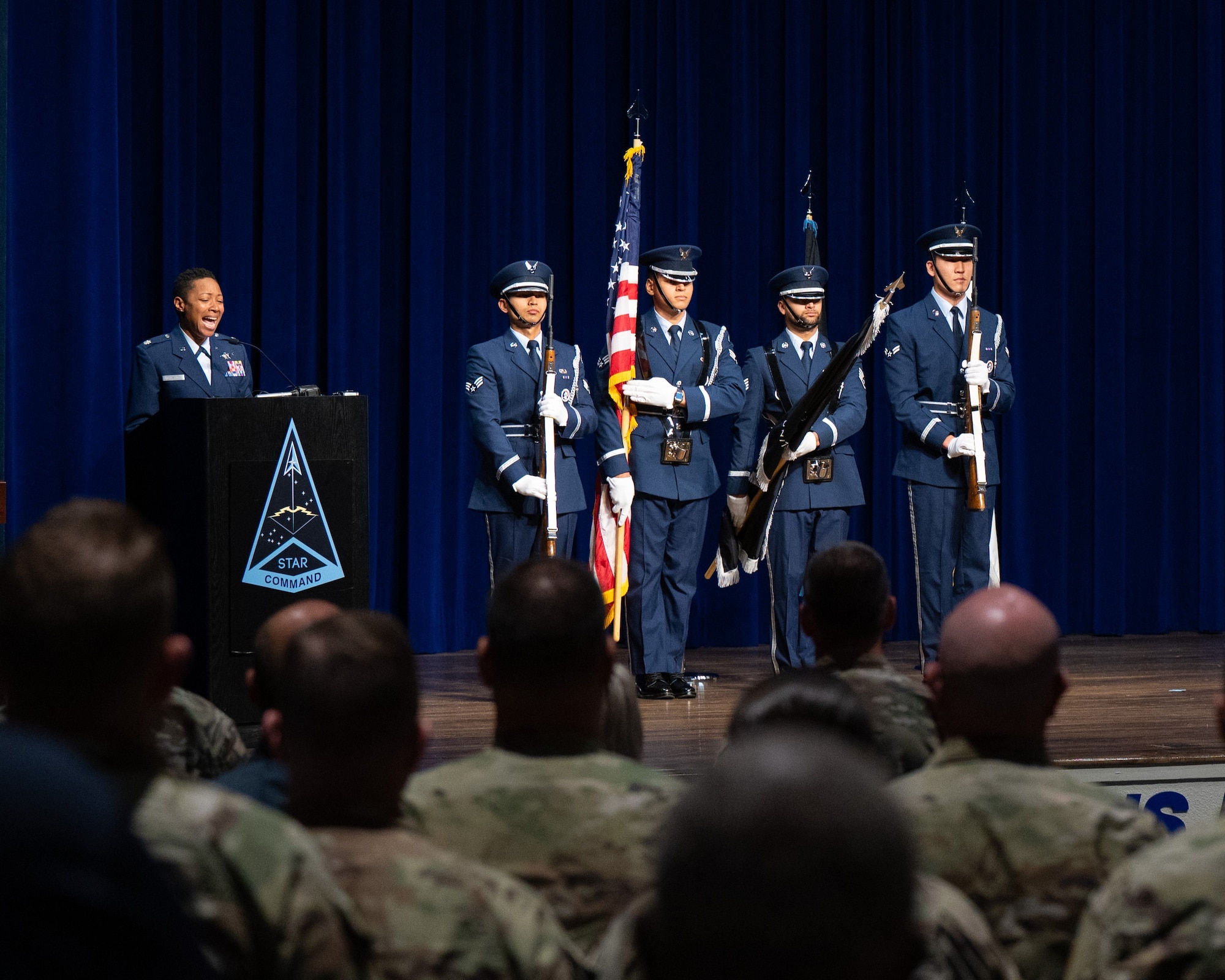 Woman singing and people in uniform standing at attention
