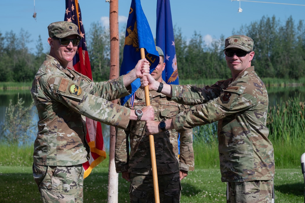 U.S. Air Force Maj. Kaleb Marsh, right, Detachment 1, 66th Training Squadron outgoing commander, relinquishes the guidon to Lt. Col. Nathan Lowry, 66th TRS commander, during a change of command ceremony at Eielson Air Force Base, Alaska, July 18, 2025.