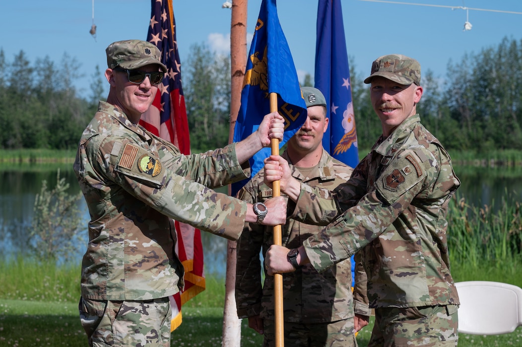 U.S. Air Force Lt. Col. Nathan Lowry, 66th TRS commander, passes the guidon to Maj. Gordon Blair, Detachment 1, 66th Training Squadron incoming commander, during a change of command ceremony at Eielson Air Force Base, Alaska, July 18, 2025.