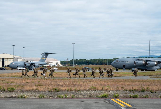 Airmen walking on a flightline with C-17 Globemaster III's in the background