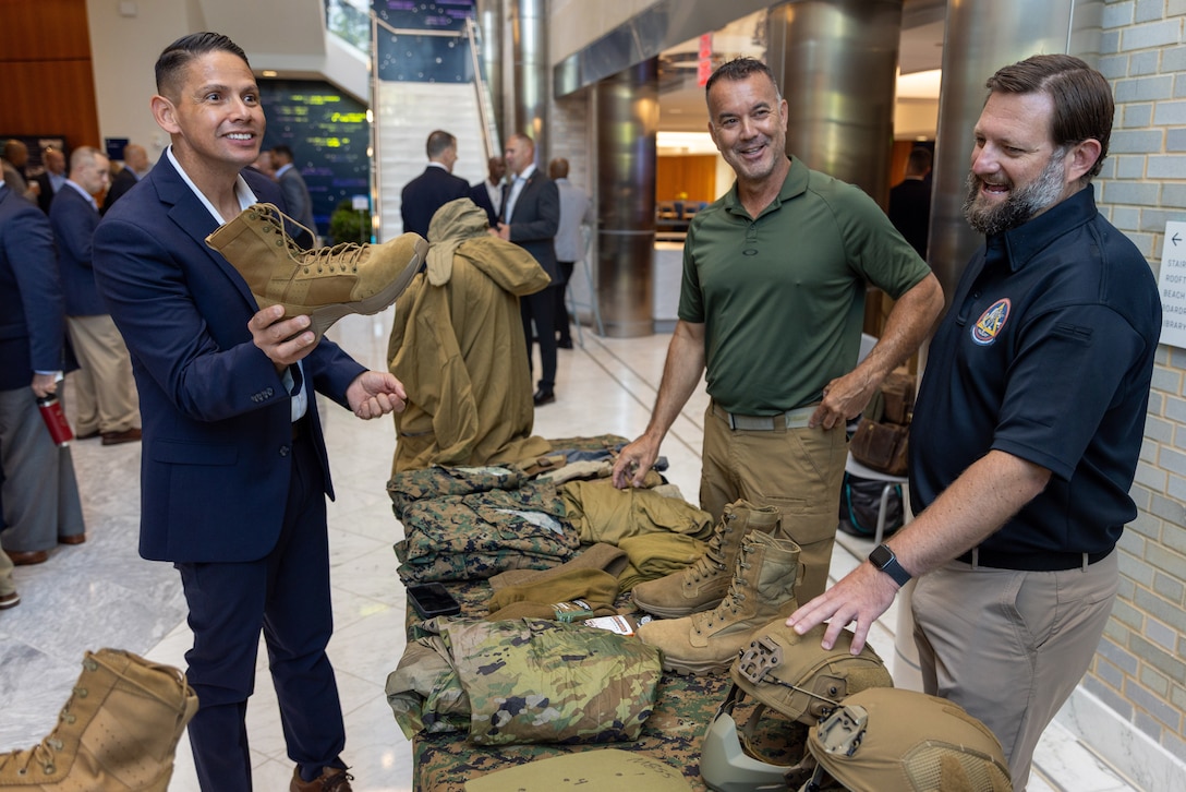 Civilian Marines Todd Towles and Trevor Scott discuss Marine Corps boots and uniforms with Sgt. Maj. Carlos A. Ruiz