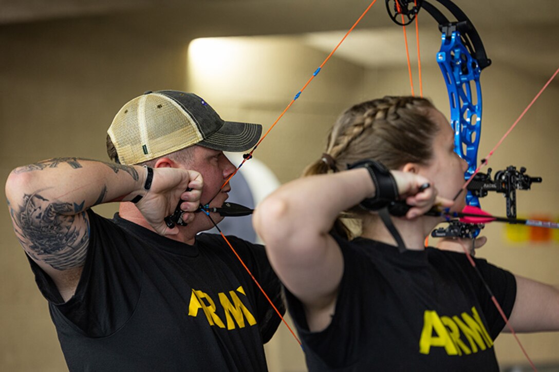 U.S. Army Staff Sgt. Tyler Pollard, left, and Capt. Samantha Frey, right, aim their bows down range while participating in archery practice during the 2025 Department of Defense Warrior Games at Fort Carson, Colorado, July 13, 2025.