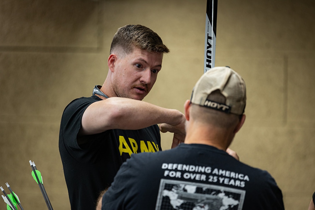 U.S. Army Staff Sgt. Coty Tuck speaks with a coach before archery practice during the 2025 Department of Defense Warrior Games at Fort Carson, Colorado, July 13, 2025.