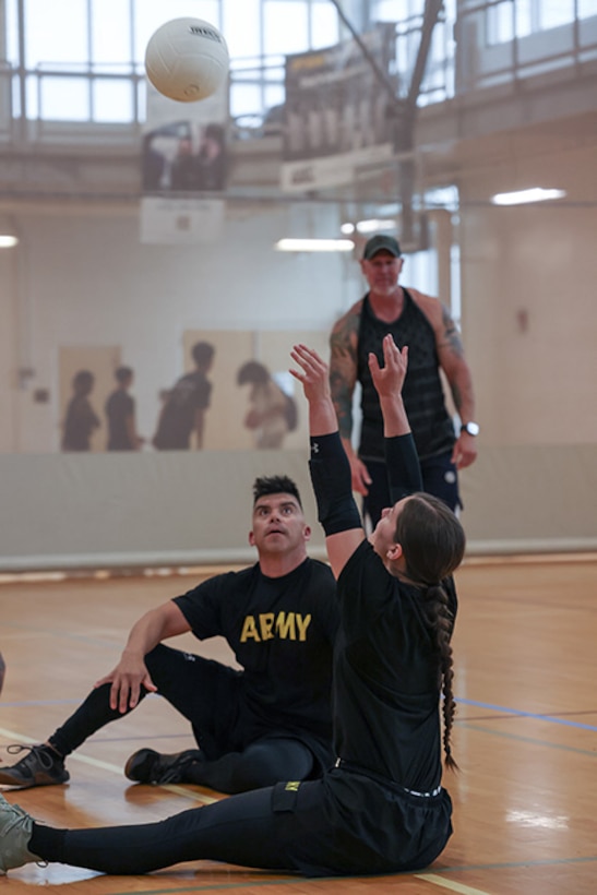 U.S. Army Sgt. 1st Class Alberto Alvarez, left, watches as Sgt. Bianca Hayden sets the ball at sitting volleyball practice during the 2025 Department of Defense Warrior Games training camp at Fort Carson, Colorado, July 15, 2025.