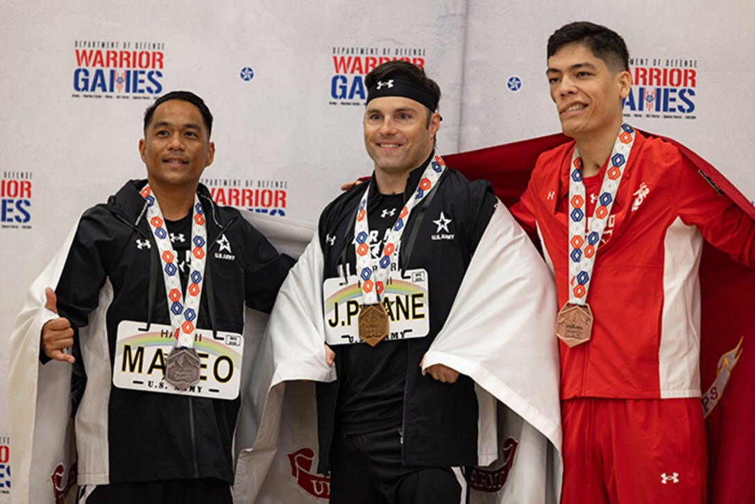 U.S. Army Staff Sgt. Nathaniel Mateo, left, silver medalist, U.S. Army veteran JP Lane, center, gold medalist, and U.S. Marine Corps Cpl. Travis Reyes, right, bronze medalist, pose for a photo during the medal ceremony at the powerlifting competition during the 2025 Department of Defense Warrior Games at Colorado Springs,