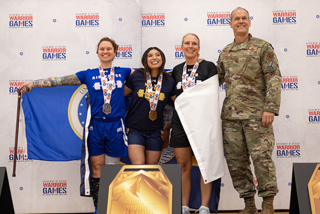 U.S. Air Force Master Sgt. Lyndie Stark, left, silver medalist, U.S. Navy Petty Officer 3rd Class Michaela Infante, center, gold medalist, and U.S. Army Maj. Amy Sparks, center-right, bronze medalist, pose for a photo with U.S. Air Force Maj. Gen. Jefferson O'Donnell, commander, Air Force Personnel Center, at the powerlifting competition during the 2025 Department of Defense Warrior Games at Colorado Springs, Colorado, July 18, 2025.