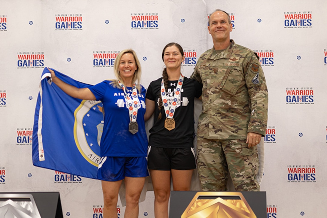 U.S. Air Force Master Sgt. Ashley Andrus, left, silver medalist, and U.S. Army Sgt. Bianca Hayden, center, gold medalist, pose for a photo with U.S. Air Force Maj. Gen. Jefferson O'Donnell, commander, Air Force Personnel Center, at the powerlifting competition at the 2025 Department of Defense Warrior Games at Colorado Springs, Colorado, July 18, 2025.
