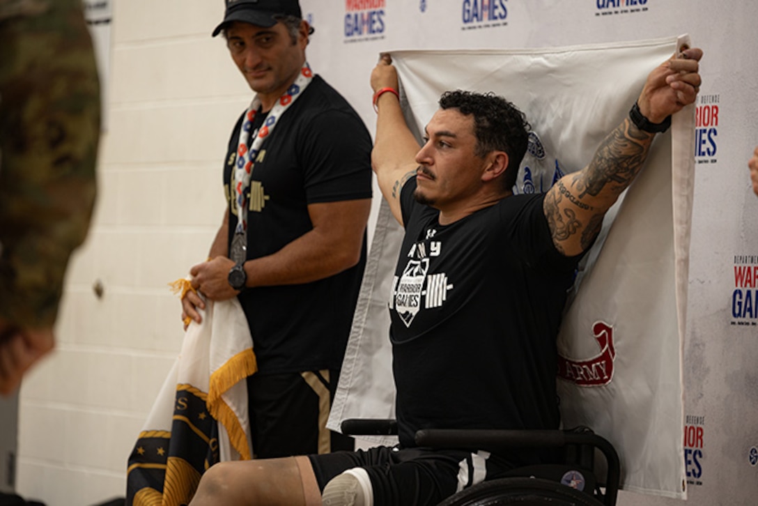 U.S. Army Retired Sgt. Jason Smith poses with the Army flag at the medal ceremony before being awarded the gold medal at the powerlifting competition during the 2025 Department of Defense Warrior Games at Colorado Springs, Colorado, July 18, 2025.