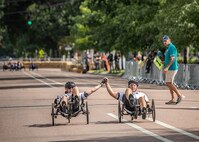 U.S. Army Sgt.1st Class Jeffrey Peters, left, and 1st Sgt. Christopher Morago, right, raise their hands in victory as they cross the finish line on their recumbent cycles during the cycling event in the 2025 Department of Defense Warrior Games, Colorado Springs, Colorado, July 19, 2025.