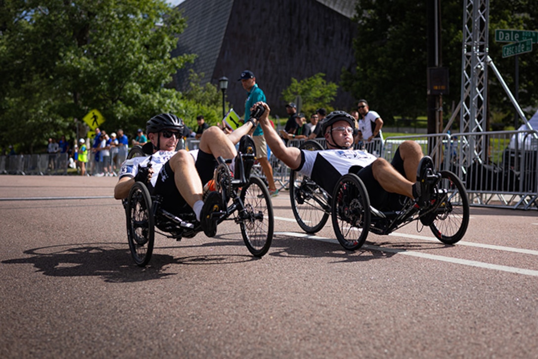 U.S. Army Sgt. 1st Class Jeffrey Peters, left, and 1st Sgt. Christopher Morago, right, cross the finish line together in the men's recumbent cycle road race at the cycling event during the 2025 Department of Defense Warrior Games at Colorado College, Colorado Springs Colorado, July 19, 2025.