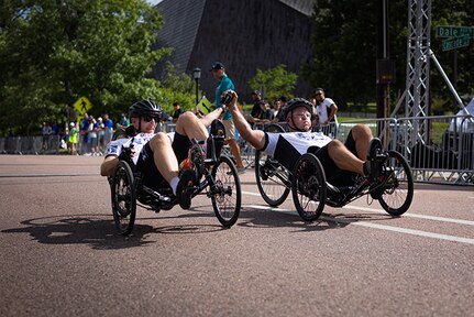 U.S. Army Sgt. 1st Class Jeffrey Peters, left, and 1st Sgt. Christopher Morago, right, cross the finish line together in the men's recumbent cycle road race at the cycling event during the 2025 Department of Defense Warrior Games at Colorado College, Colorado Springs Colorado, July 19, 2025.