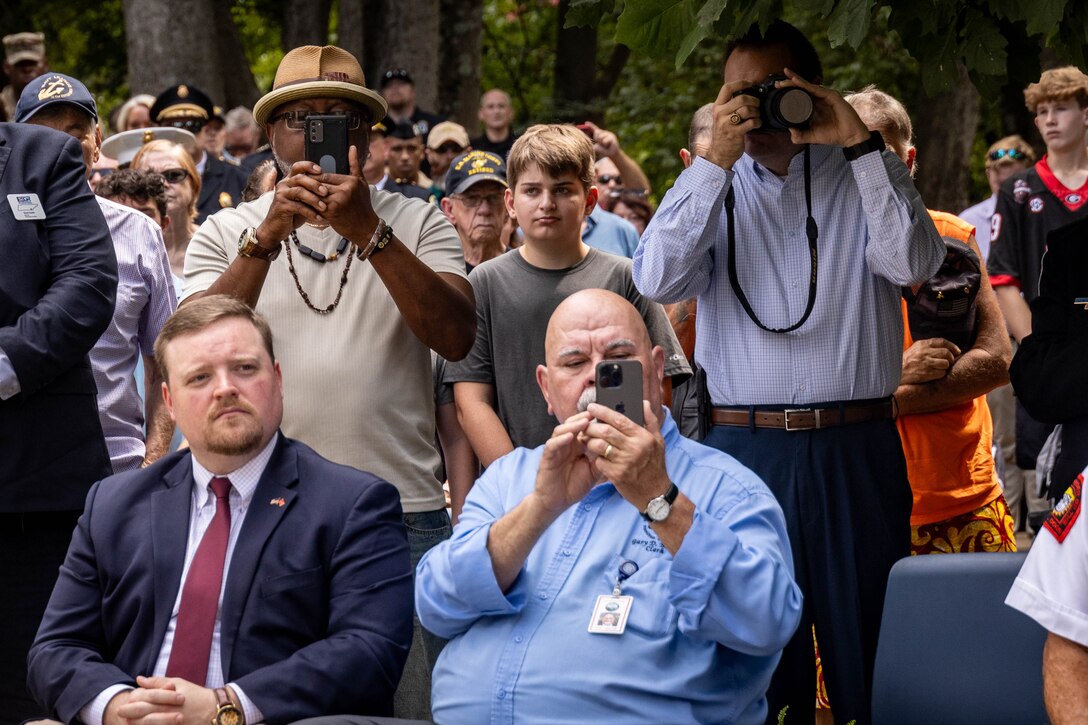 Civilians of Chattanooga take photos of wreath placements during the fallen five memorial ceremony at the Wreath of Honor Fallen Five Memorial Park, Chattanooga, Tennessee, July 16th, 2025. The Wreath of Honor Fallen Five Memorial honors the loss of five U.S. service members tragically killed July 16th, 2015, in a terrorist attack in Chattanooga. The placement of wreaths symbolizes gratitude, respect and remembrance for those who served and sacrificed for their country. (U.S. Marine Corps photo by Lance Cpl. Edward Spears)