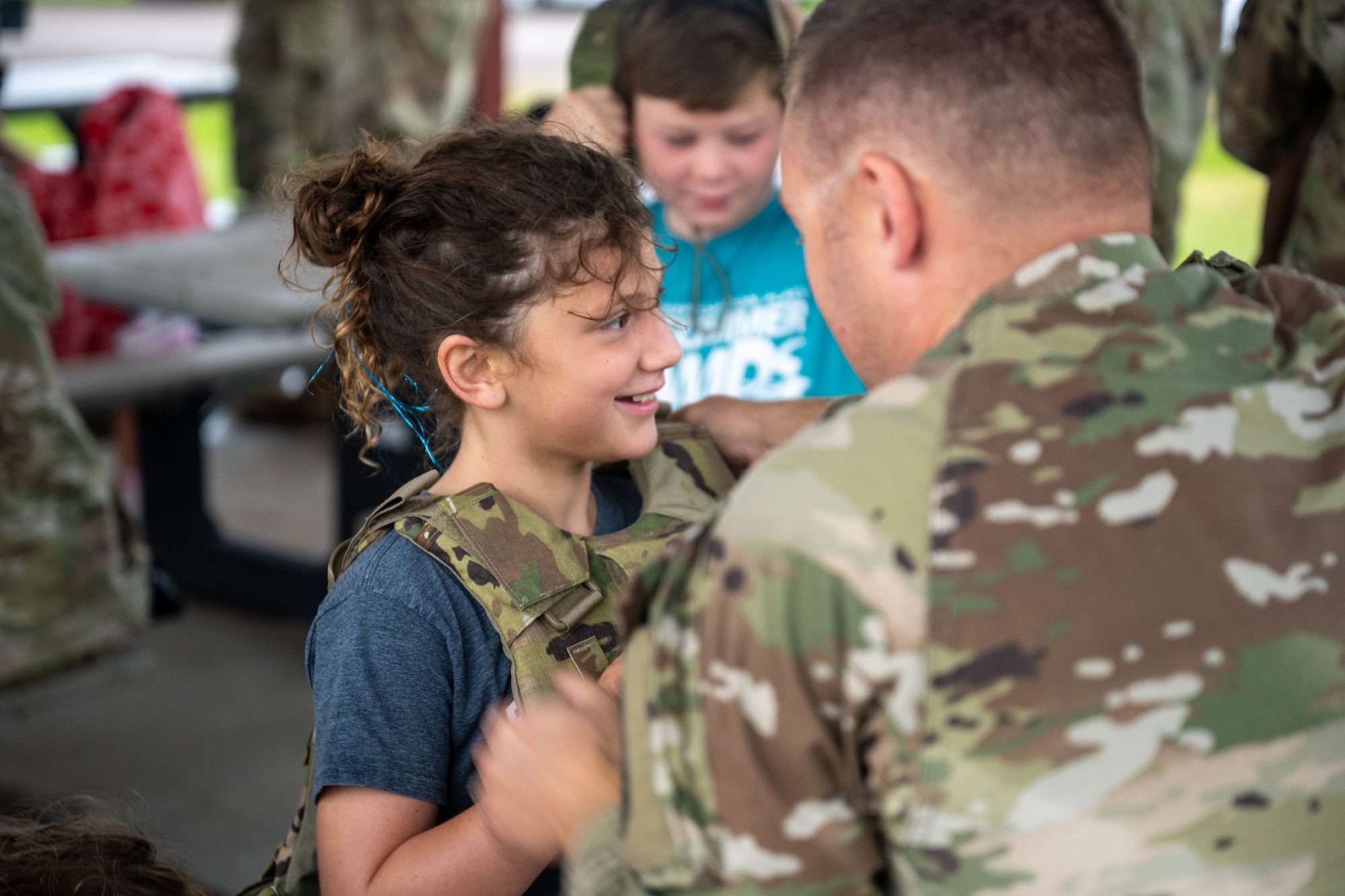 A child learns how to properly wear a plate carrier