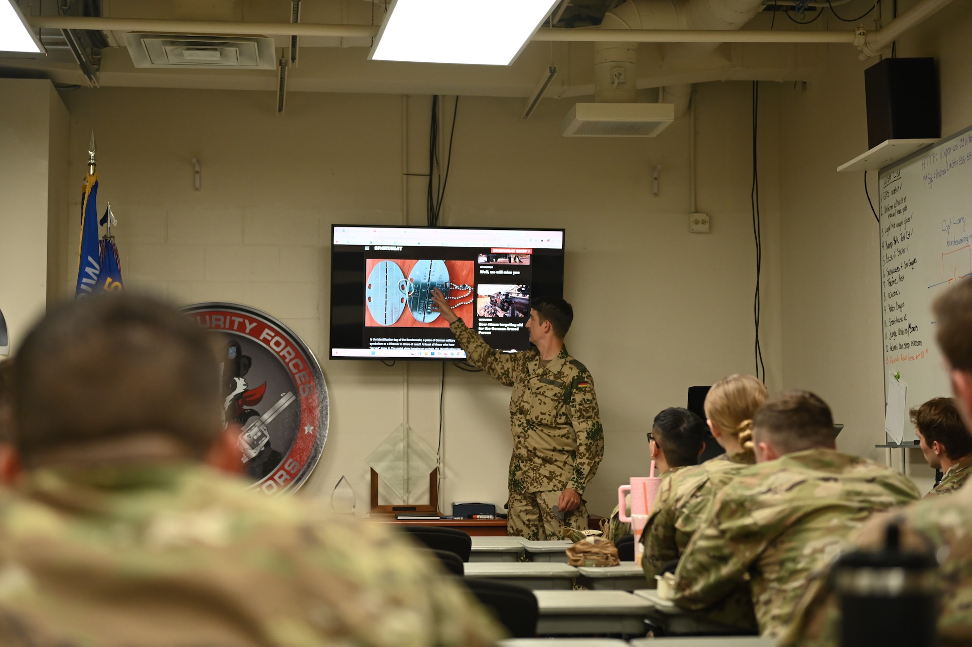 German Air Force Capt. Matthias Lang, Bravo Platoon Leader assigned to the 10th Company Home Defense Force Regiment #1, Germany, gives Airmen assigned to the 115th Fighter Wing a lesson about German identification tags during the Military Reserve Exchange Program at Truax Field, Wisconsin, June 10, 2025. The MREP provides an opportunity for professional development by allowing participants to train in a duty assignment similar to wartime. (U.S. Air National Guard photo by Ms. Fallon Riley)