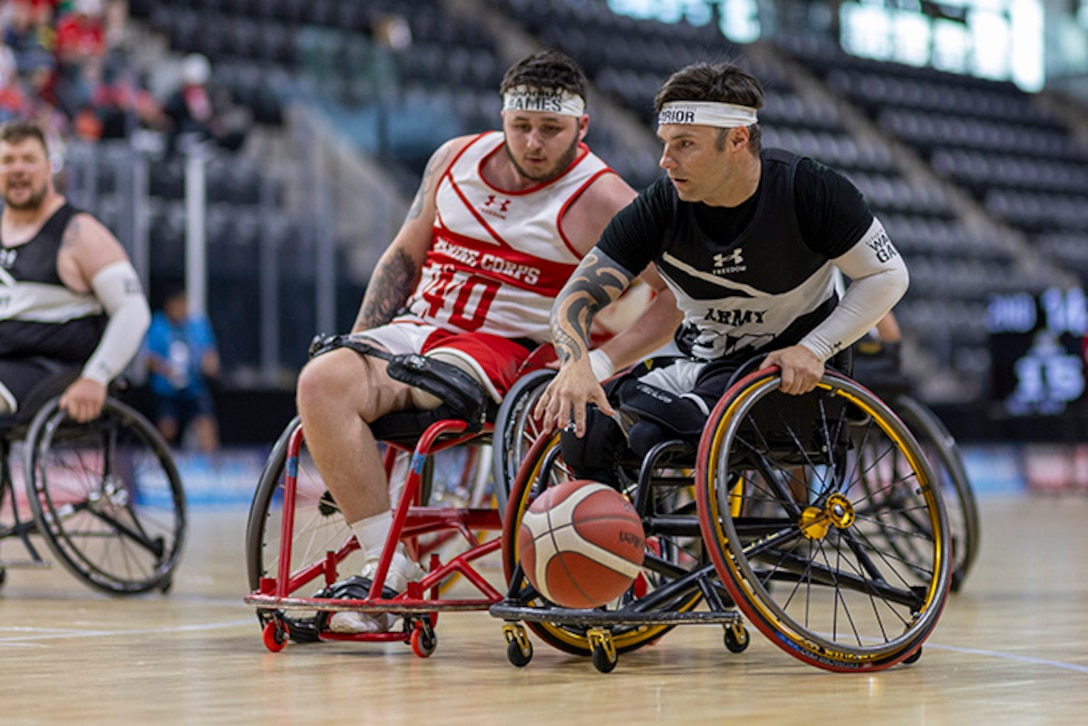 Retired U.S. Army Spc. JP Lane brings the ball up court while fighting for position in the wheelchair basketball game against Team Marine Corps during the 2025 Department of Defense Warrior Games at Colorado Springs, Colorado, July 19, 2025.