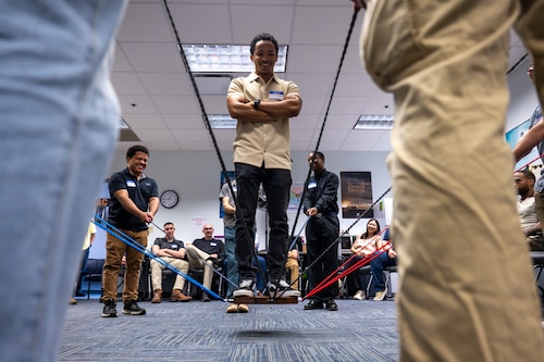 Airman 1st Class Greyson Broussard-Tavares, 375th Communications Squadron, balances on a suspended platform as fellow Airmen support him with color-coded cords during a Wingman Guardian Connect exercise.