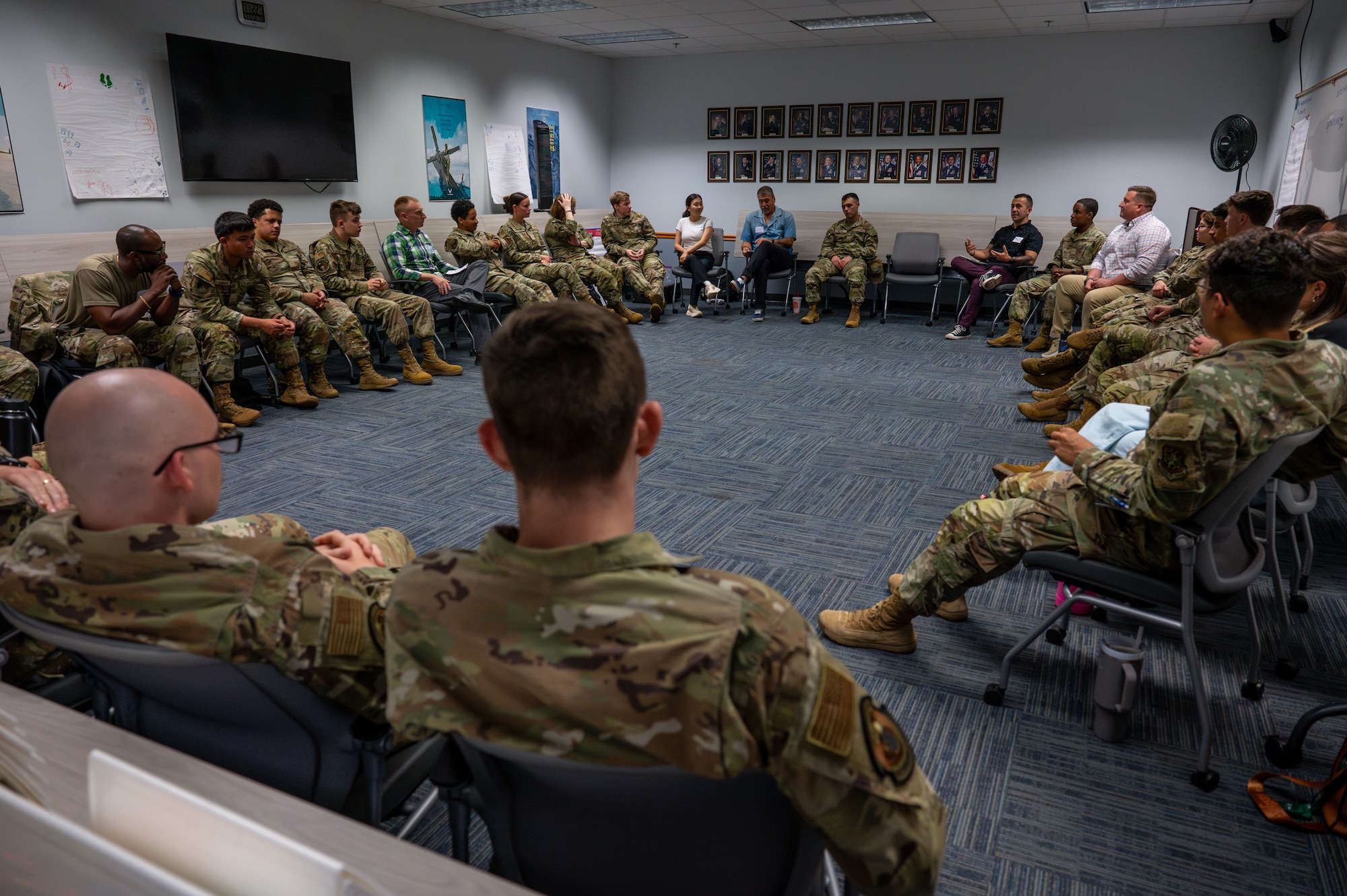 Airmen sit among facilitators in a circular formation as a Wingman Guardian Connect instructor leads a discussion during the First Term Airmen Course.